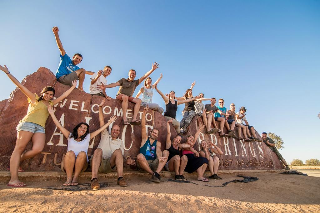 Group of travelers at the "Welcome to Alice Springs" sign in Central Australia.