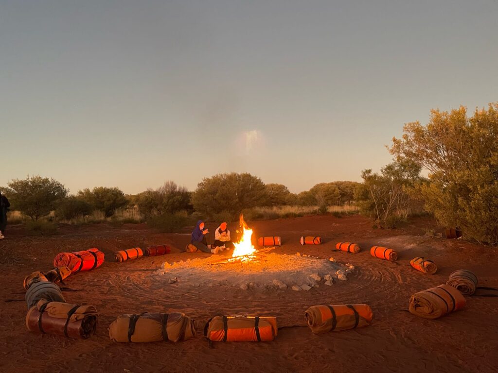 A circle of swags around a morning campfire in the Australian outback.