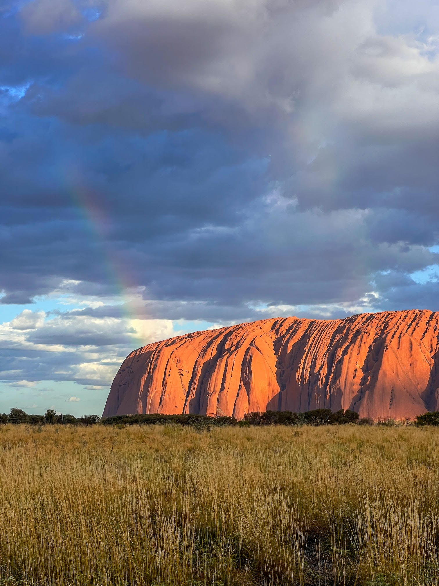 A beautiful rainbow arches over Uluru, highlighting its majestic presence in the heart of the Australian outback.