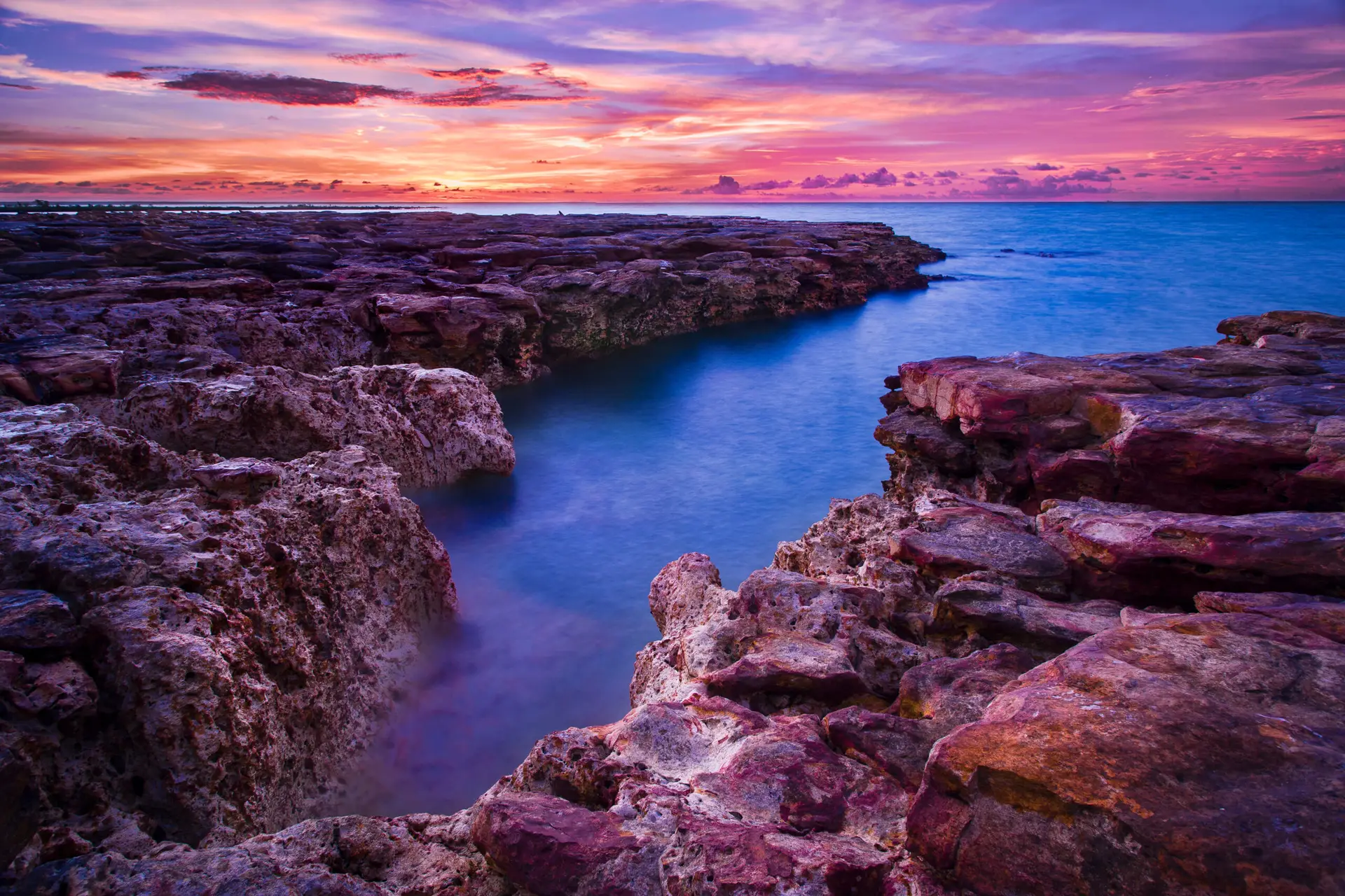 A breathtaking sunset over the rocky coastline of Nightcliff in Darwin, Australia, showcasing the vibrant colors and serene beauty of the ocean.