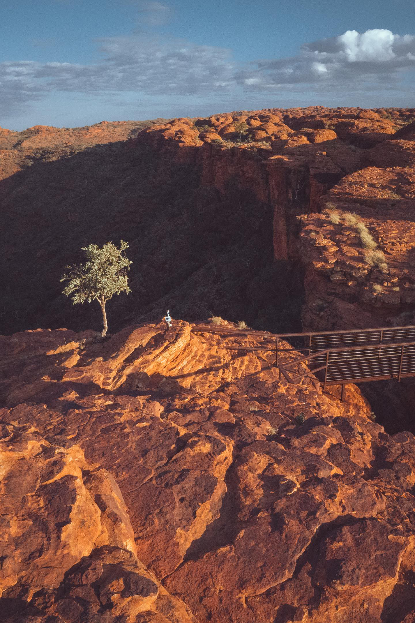 A sign stands on a rocky outcrop in Kings Canyon, Central Australia, highlighting the rugged beauty and vastness of the landscape. Photo credit: Nastasia Klopp. Instagram: @nastasiaklopp