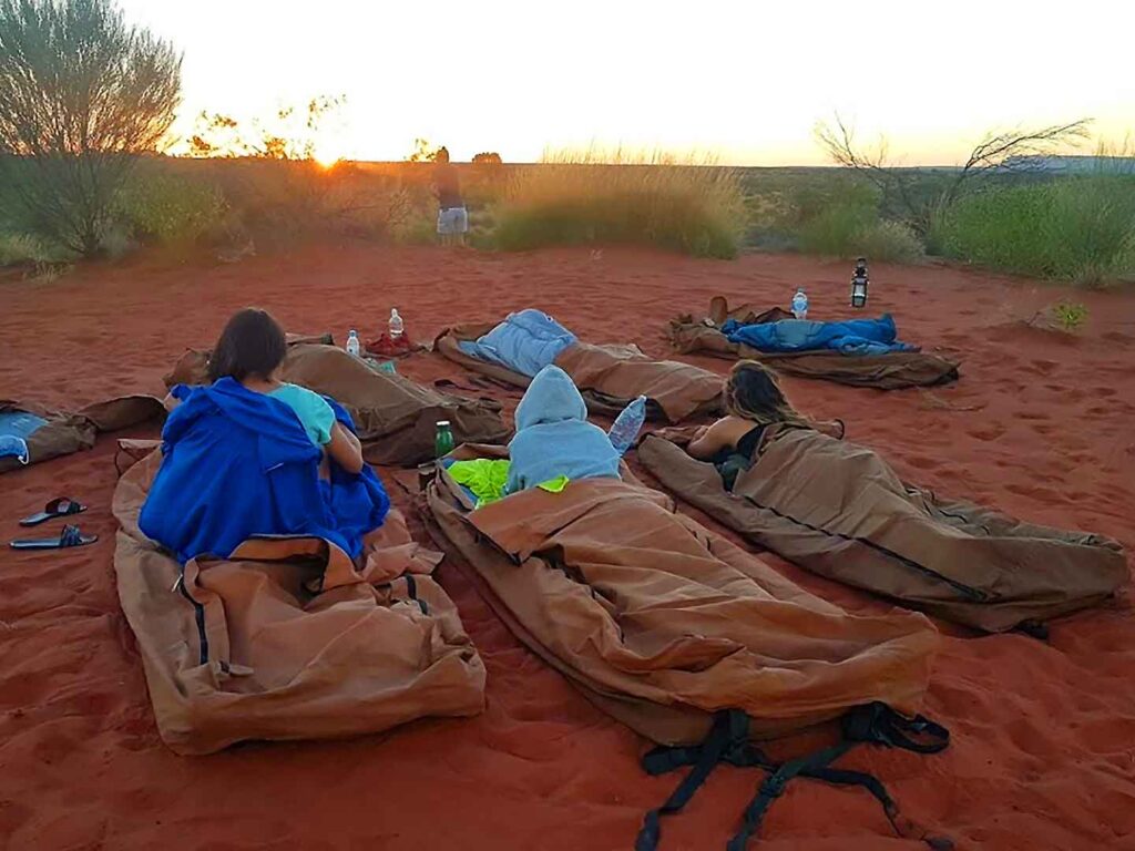 Tour group relaxing in swags at sunset during a Mulgas Adventures tour in the Australian Outback.
