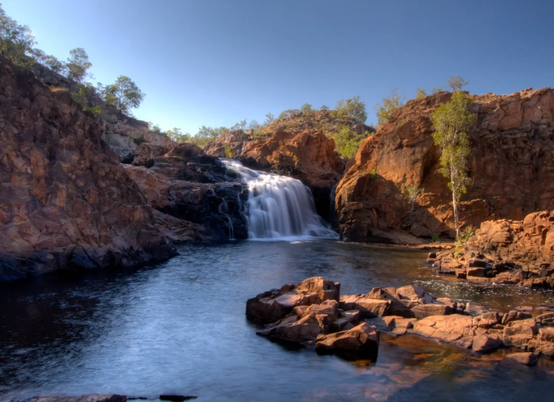 Edith Falls cascading into a serene pool surrounded by rocky cliffs and greenery.